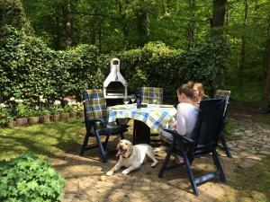 two women sitting at a table with a dog in front at Forsthaus Wendt in Timmendorfer Strand