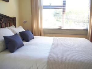 a bedroom with a white bed with two blue pillows at Loeriewood Garden Apartment, Hunters Home in Knysna