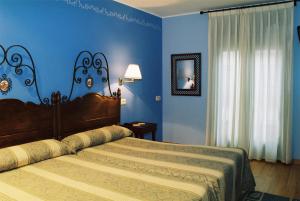a bedroom with two beds and a blue wall at Hotel Conventin in Villaviciosa