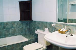 a bathroom with a toilet and a sink and a tub at Hotel Conventin in Villaviciosa