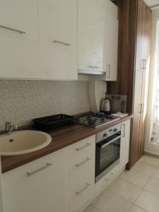 a kitchen with white cabinets and a sink at iHome Apartment 4.0 in Pécs