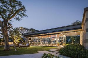a large building with glass windows and a tree at rain condo Cha-am 2 bedroom by Napa in Cha Am