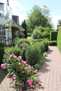 un jardín con flores rosas y una pasarela de ladrillo en Forsthaus Wendt, en Timmendorfer Strand