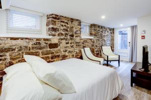 a bedroom with a white bed and two chairs at L'Adresse sur Grande-Allée Lofts in Quebec City