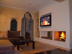 a living room with a fireplace and a tv on a wall at Tweets Hotel in Essaouira