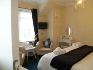 um quarto de hotel com uma cama, uma cadeira e um espelho em Greenlaw Guest House em Gretna Green