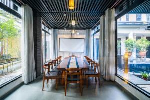 uma sala de jantar com mesa, cadeiras e janelas em Lijiang Gemmer Hotel em Lijiang