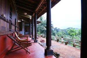 a porch of a house with a chair on it at Malayoram Heritage Villa Munnar in Kūmudi