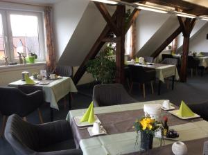 a dining room with tables and chairs and windows at Hotel am Maibaum in Neuenrade