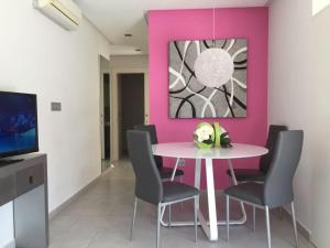 グアルダマル・デル・セグラにあるApartamentos Marjal 3のピンクの壁のダイニングルーム(テーブル、椅子付)