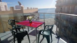 a red table and chairs on a balcony with the ocean at Apartamentos Marjal 3 in Guardamar del Segura