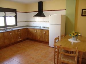 a kitchen with a table and a white refrigerator at Los Trulls d´Auligué in Pobla de Masaluca
