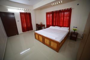 a bedroom with a large bed and red curtains at Indeevaram Residency in Trivandrum