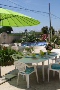 een tafel met twee stoelen en een groene parasol bij Chambres d'hôtes - Les Palmiers in Corseul
