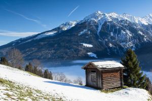 a wooden cabin on a snow covered hill with a mountain at Apartment Wanger in Neukirchen am Großvenediger