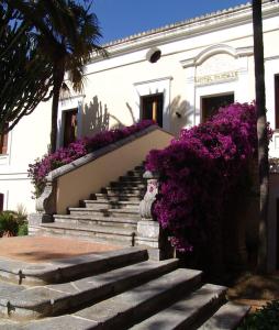 a white building with purple flowers on the stairs at hotel Ducale in Diamante