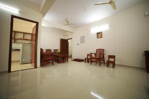 a living room with chairs and a table and a refrigerator at Indeevaram Residency in Trivandrum