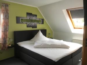 a bedroom with a bed with white sheets and a window at Hotel am Maibaum in Neuenrade