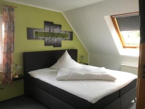 Schlafzimmer mit einem Bett mit weißer Bettwäsche und einem Fenster in der Unterkunft Hotel am Maibaum in Neuenrade