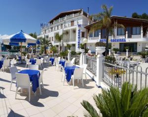patio z niebieskimi stołami i krzesłami przed budynkiem w obiekcie Hotel Orchidea w mieście Peschici