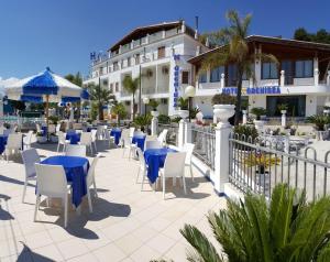 a patio with blue tables and chairs in front of a building at Hotel Orchidea in Peschici