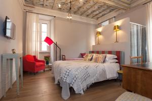 a bedroom with a bed and a red chair at Casa Fabbrini Fancy Suites in Rome