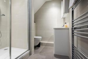 a bathroom with a toilet and a glass shower at The Paddington Studio - Cool & Stylish 1BDR Mews in London