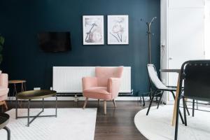a living room with blue walls and a pink chair at The Paddington Studio - Cool & Stylish 1BDR Mews in London
