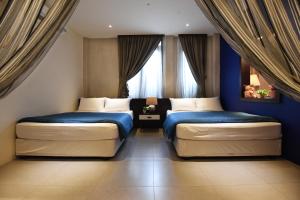 two beds in a room with blue walls and windows at Backyard Rio Melaka in Malacca