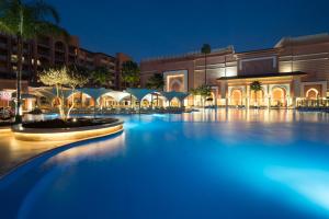 a large swimming pool in a resort at night at Savoy Le Grand Hotel Marrakech in Marrakech