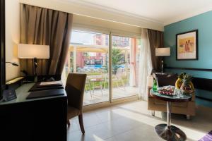 a hotel room with a desk and a table with a table at Savoy Le Grand Hotel Marrakech in Marrakech