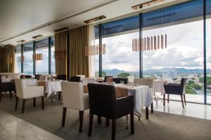 a restaurant with white tables and chairs and large windows at Grand Plaza Hotel Nampula in Nampula