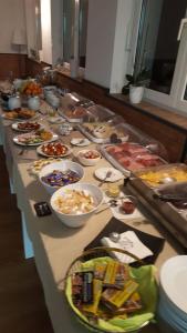 einem langen Tisch voller Schüsseln und Teller mit Lebensmitteln in der Unterkunft Spielzeughotel Sonneberg in Sonneberg