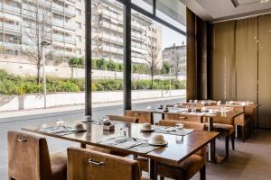 a restaurant with wooden tables and chairs and a large window at Hotel Exe Barcelona Gate in Sant Joan Despí