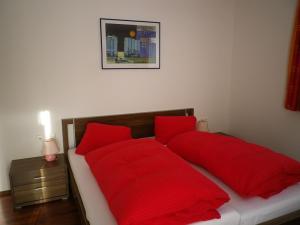 Una cama roja con almohadas rojas encima. en Apartment Tonitz, en Sankt Jakob in Defereggen