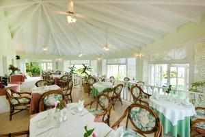 Hotel Villa Serena في لاس غاليراس: غرفة طعام مع طاولات بيضاء وكراسي ونوافذ