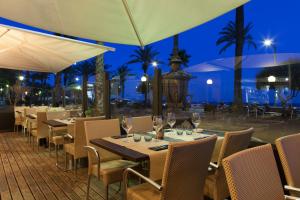 a restaurant with tables and chairs and a pool at night at URH Excelsior in Lloret de Mar