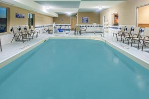 a swimming pool with chairs and tables in a building at Baymont by Wyndham South Haven in South Haven