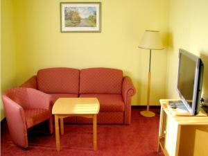 a living room with a couch and a table and a tv at Hotel am Platz in Hohenmölsen