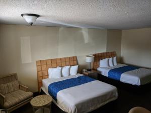 una stanza d'albergo con due letti e una sedia di Travelodge by Wyndham Clovis a Clovis