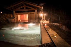 a swimming pool at night with candles in front of a cabin at Il Nido del Casalot in Frassino