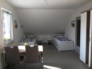ニュルンベルクにあるEibach Appartmentのベッド2台、テーブル、椅子が備わる客室です。