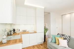 a kitchen with white cabinets and a couch at Apartamenty Złota 15 in Kielce