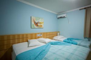 two twin beds in a room with a blue wall at Hotel Saint Louis in Luis Eduardo Magalhaes