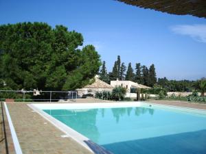 a large blue swimming pool in front of a house at Pozzo Di Mazza in Siracusa