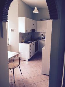 una cucina con armadi bianchi, tavolo, tavolo e sedia di Casa Bertocco a Canale Monterano