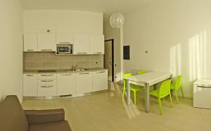カンピョーネ・デル・ガルダにあるCampione Ora apartments by Gardadomusmeaの白いキャビネット、テーブルと椅子付きのキッチンが備わります。