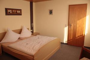 a bedroom with a bed with white sheets and a door at Landgasthof Rademacher in Finnentrop