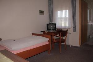 a bedroom with a bed and a desk with a television at Landgasthof Rademacher in Finnentrop