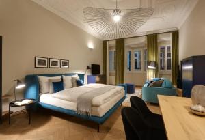 a large bedroom with a blue bed and a couch at Arcade Apartments in Bolzano